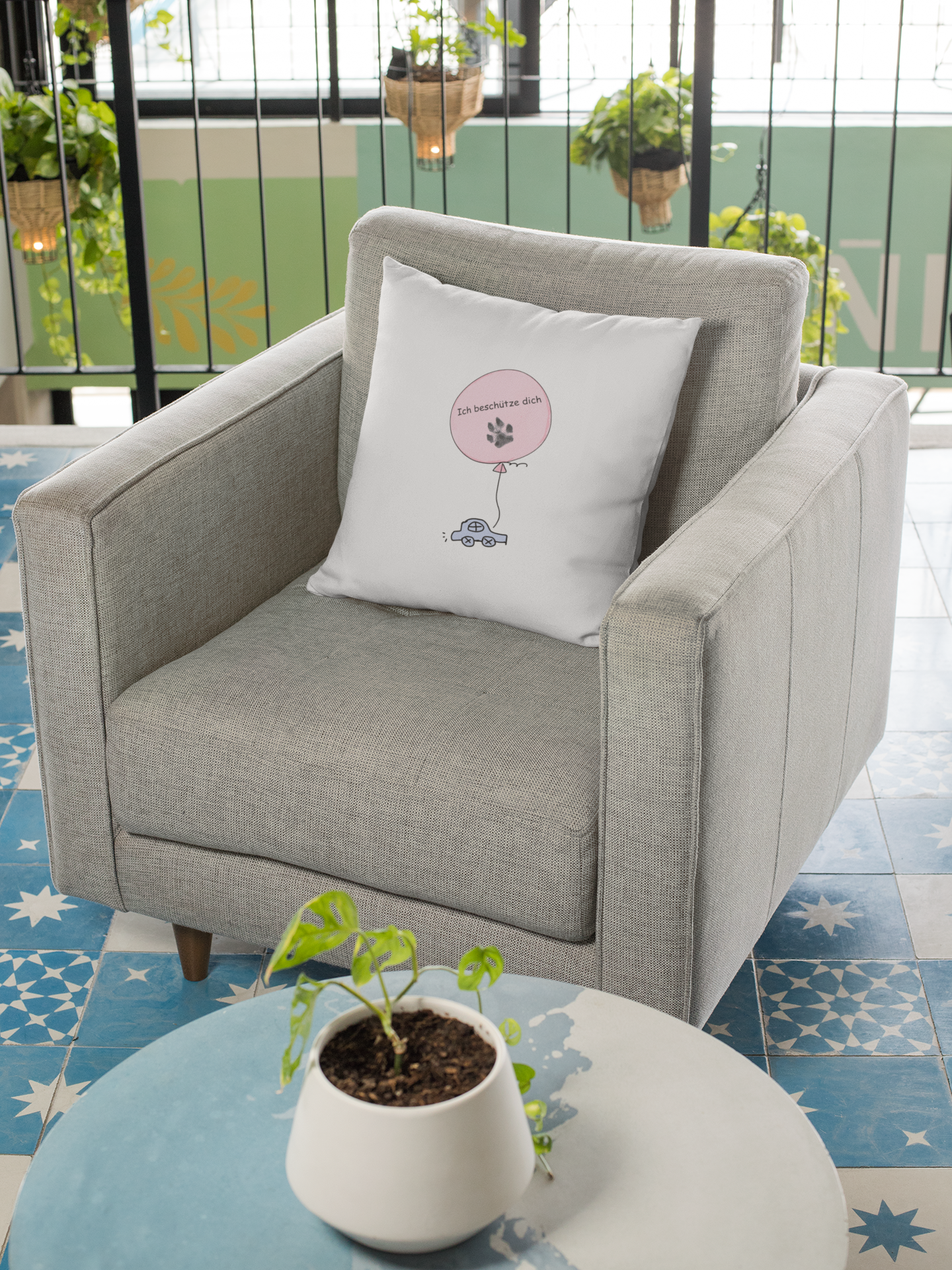 Weißes Dekokissen Hundepfote von Milki´s Way mit rosa Ballonmotiv auf grauem Sessel im Wohnzimmer