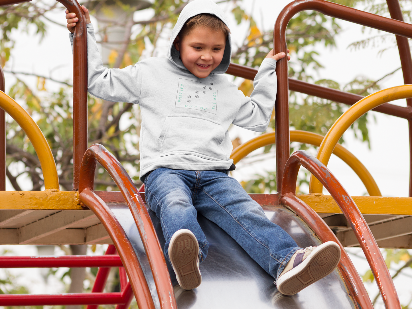 Kinder Hoodie mit Hundepfote von Milkis Way in hellgrau, getragen von lachendem Jungen auf Spielplatzrutsche