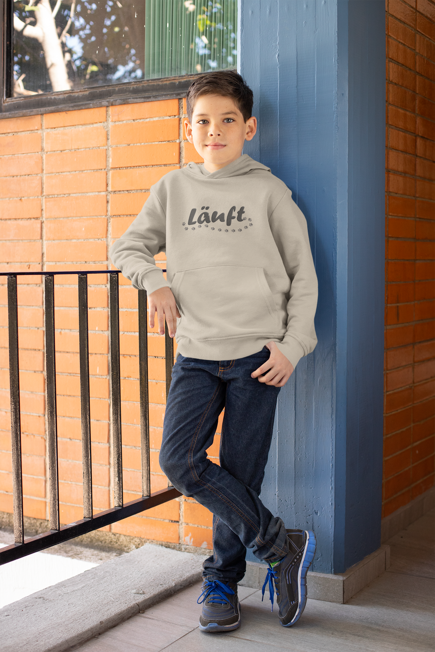 Kinder Hoodie mit Hundepfoten in beige von Milkis Way, getragen von Junge vor Ziegelwand