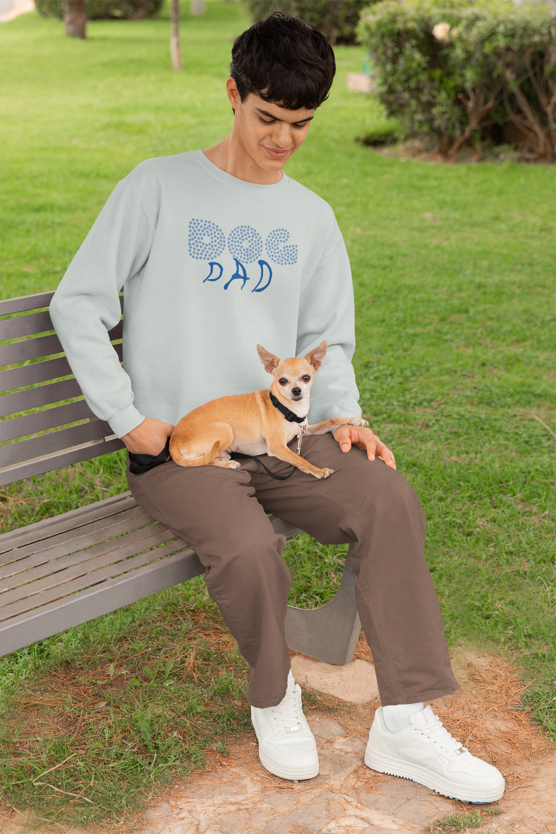 Milkis Way Sweatshirt mit Hundepfote Print getragen von sitzendem Mann mit kleinem Hund auf dem Schoß im Park